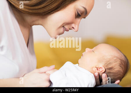 Loving Mother Cuddling Baby son couchage sur lap à Accueil Banque D'Images