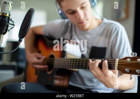 Adolescent qui joue de la guitare et l'enregistrement de la musique à la maison Banque D'Images