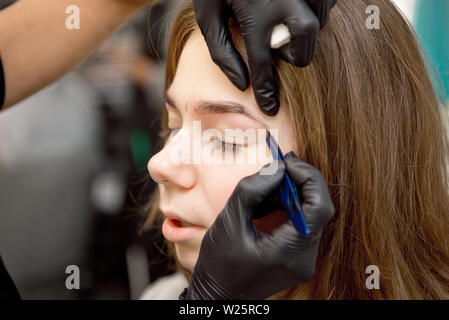 Ce faisant, maquilleuse maquillage professionnel de jeune femme près du miroir en beauté. Banque D'Images