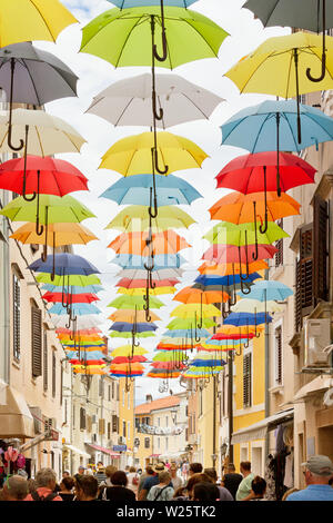Novigrad, Istrie, Croatie, Europe - 3 septembre 2017 - Les touristes en se promenant dans une ruelle avec parasols colorés au-dessus Banque D'Images