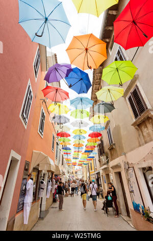 Novigrad, Istrie, Croatie, Europe - 3 septembre 2017 - Les touristes en se promenant dans la vieille ville de Novigrad avec parasols au-dessus d'eux Banque D'Images