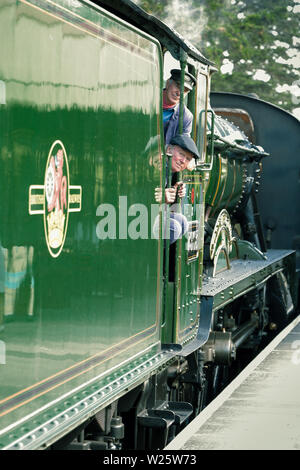 Un train à vapeur GWR vintage en tirant moteur Broadway gare ferroviaire patrimoniale en tant que pilote le moteur et fireman look out Banque D'Images