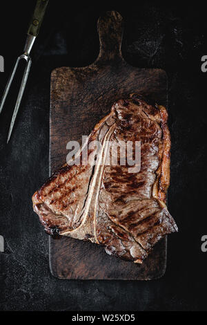 Sèche Haut grillé de T-bone steak sur Planche rustique foncé. Boeuf USDA. Banque D'Images