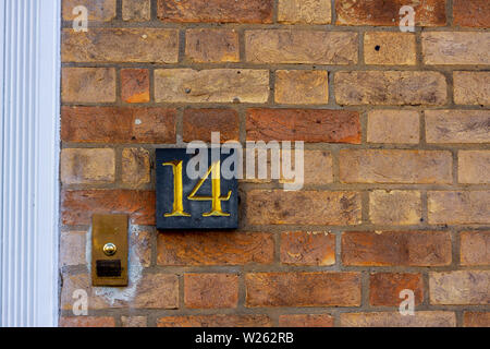 Chambre numéro 14 avec les 14 en or sur une plaque noire fixée à un mur de brique rouge Banque D'Images