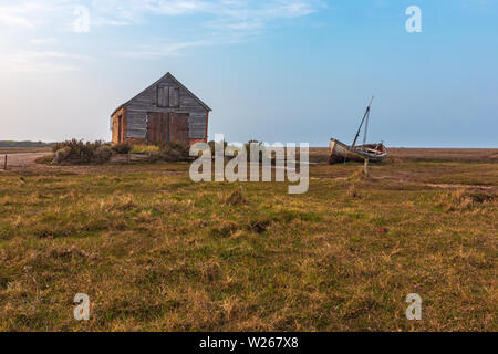 Paysage côtier de Saltmarsh autour de l'ancienne grange à charbon avec pêche Bateau sur son côté près de Thornham dans le nord de Norfolk Banque D'Images