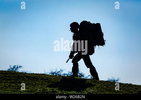 SENNYBRIDGE, ROYAUME-UNI. 27 mars 2019. Un Royal Marine se dirige vers le coucher du soleil transportant sa bergen et son fusil à travers la zone d'entraînement de Sennybridge. Banque D'Images