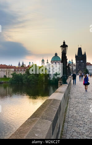 Prague, République tchèque - 27 juin 2019 : Les gens qui marchent sur l'historique pont Charles tôt le matin. Lever du soleil la lumière. Célèbre Quartier Gothique et site touristique populaire. La Bohême, République tchèque. Banque D'Images