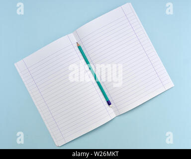 Ordinateur portable blanc isolé avec papiers et bordée d'un crayon vert sur fond bleu clair. Banque D'Images