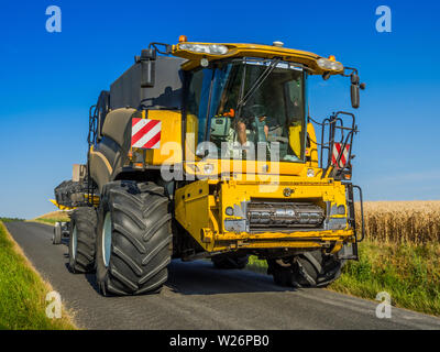 'New Holland' à la moissonneuse-batteuse sur la voie publique - France. Banque D'Images