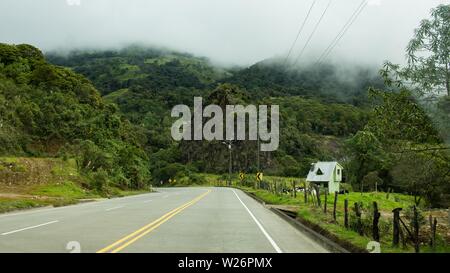 Belle photo d'une route vide incurvée à la campagne avec des nuages étonnants pendant une journée brumeuse Banque D'Images