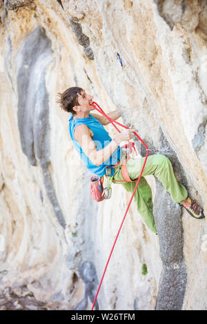 Rock climber aller à corde clip alors que l'escalade difficile itinéraire sur falaise Banque D'Images