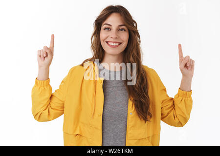 Bien excité optimiste européen curly girl pointing hands up montrant cool nouvelle promo smiling rugueux partage joyeusement lien intéressant recommander t Banque D'Images