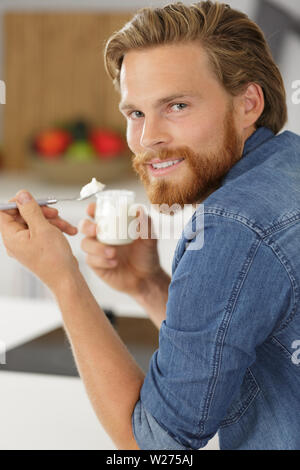 Homme heureux de manger des yaourts à la maison Banque D'Images