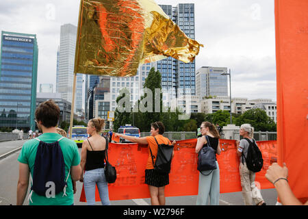 Francfort, Allemagne. 6 juillet 2019. Les marches de protestation à travers le centre ville de Francfort, avec les gratte-ciel peut être vu dans l'arrière-plan. Plus de 1 000 personnes ont défilé à Francfort, à appeler pour enregistrer les réfugiés, à la fin de la criminalisation de sauvetage en mer et une disposition de ports pour enregistrer les réfugiés en Europe. Cette manifestation s'inscrivait dans le cadre d'une large protestation Seebrucke allemande sous le slogan de "l'état d'urgence de l'humanité", qui a eu lieu après 3 Sea-Watch allemand le capitaine Carola Rackete a été arrêté en Italie pour secourir les réfugiés en Méditerranée et de les traduire en Italie. Banque D'Images