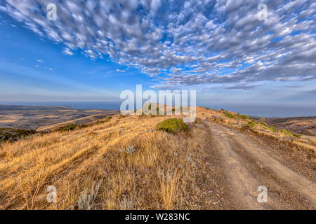 Rocky Road sur hill top par paysage méditerranéen sur l'île de Chypre avec en arrière-plan de l'océan. Le climat semi-aride chaud type BSh a corr Banque D'Images