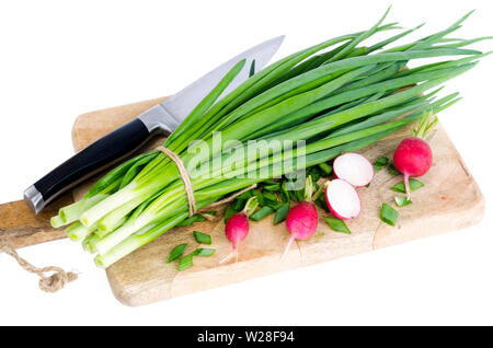 Oignons verts frais, radis rouge sur une planche à découper. Banque D'Images