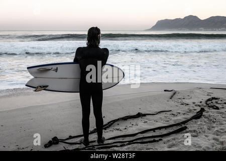 Un surfeur de St James sur Danger Beach envisage de retourner dans la mer tout en regardant une autre série de vagues sur la péninsule du Cap, Afrique du Sud Banque D'Images