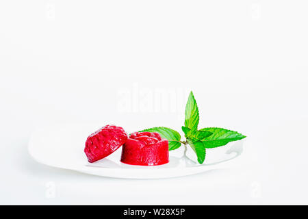 Berry gelée avec une feuille de menthe sur une plaque blanche close-up. Banque D'Images