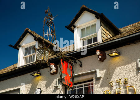 UK, Cumbria, Hawkshead, Main Street, Red Lion Pub signe avec man holding pig et jouant de la cornemuse les figures ci-dessous à l'étage supérieur des lucarnes Banque D'Images