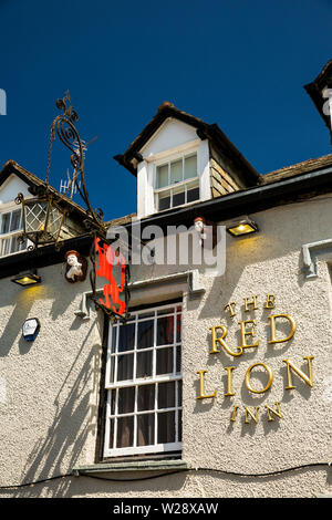 UK, Cumbria, Hawkshead, Main Street, Red Lion Pub signe avec man holding pig et jouant de la cornemuse les figures ci-dessous à l'étage supérieur des lucarnes Banque D'Images