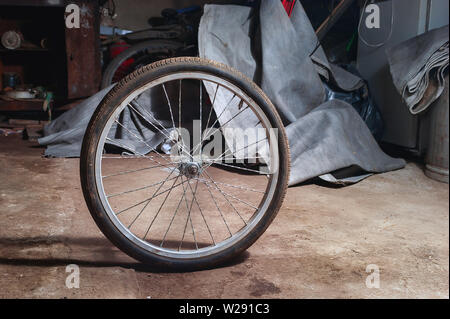 Roue de vélo sale sur le sol d'une maison malpropre Garage. Banque D'Images