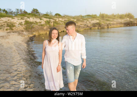 Couple holding hands walking on beach romantique sur vacances voyages vacances. Coucher du soleil et le sable doré de la copie pour l'espace. Jeune couple aimant Banque D'Images