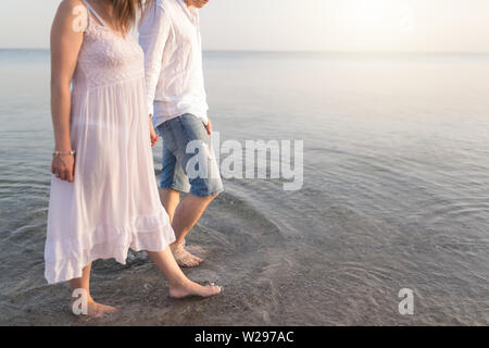 Couple holding hands walking on beach romantique sur vacances voyages vacances. Gros plan du corps et le sable doré de la copie pour l'espace. Jeune couple aimant Banque D'Images