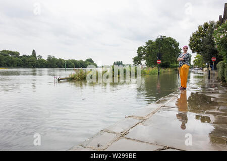 Une jeune femme envisagé de la laisse des hautes eaux et des inondations sur la Tamise à Chiswick, à l'ouest de Londres, Royaume-Uni Banque D'Images