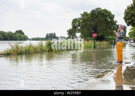 Une jeune femme envisagé de la laisse des hautes eaux et des inondations sur la Tamise à Chiswick, à l'ouest de Londres, Royaume-Uni Banque D'Images