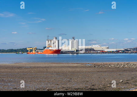 Marée basse le long de Weston shore avec vue sur les quais de Southampton avec du Normand l'Est Pacifique - une construction off shore navire amarré, Southampton, UK Banque D'Images