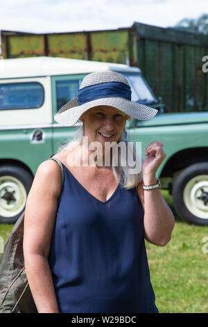 90e Kent County Show, Detling, le 6 juillet 2019. Femme dans un chapeau de paille vêtu d'un haut bleu se trouve en face d'un Landrover. Banque D'Images