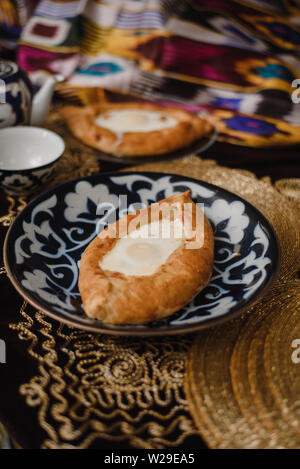 Adjara khachapuri sur la table. l'est dans d'oeufs frais pain chaud sur les plateaux orientaux est dans un restaurant. Banque D'Images