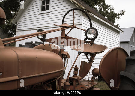 Tracteur Antique Rouge Grange. Tracteur ancien rouge stationné devant une grange blanche dans le Midwest américain Banque D'Images