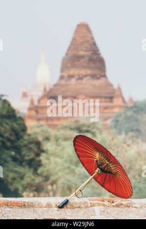 Birman traditionnel parapluie rouge avec Ananda temple le contexte de Bagan, Myanmar. Orientation verticale Banque D'Images