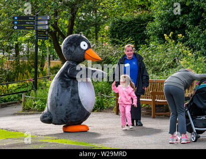 Une petite fille des courbes pour Penny-guin Gentoo pingouin le Zoo d'Édimbourg, mascot, Édimbourg, Écosse, Royaume-Uni Banque D'Images