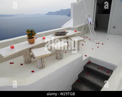 Table et chaises avec des pétales de rose rouge romantique Oia Santorini, Cyclades, Grèce Banque D'Images