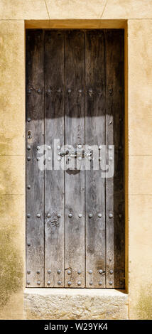 Porte en bois massif avec rivets dans son cadre de pierres vieillies, porte fermée - orientation portrait vertical Banque D'Images