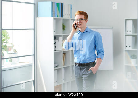 Contemporary young businessman talking on mobile phone à l'un de clients Banque D'Images