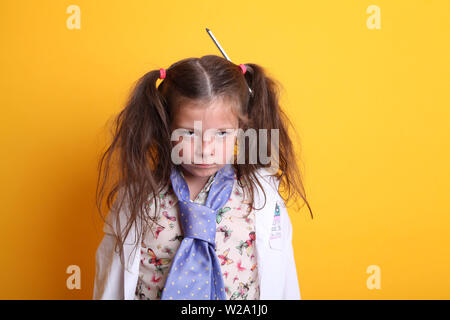 M. - Science jeune petite fille / Femme - Age 7 - l'enfant regarde en colère ou grincheux à l'appareil photo allumé arrière-plan jaune Banque D'Images