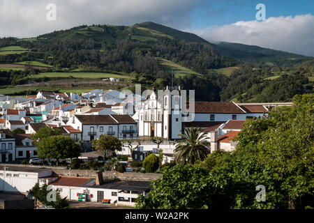 La ville, avec ses maisons blanches et une église construite dans un style traditionnel portugais. Montagnes et un ciel nuageux dans l'arrière-plan. Agua de Pau, Sao Miguel. Banque D'Images