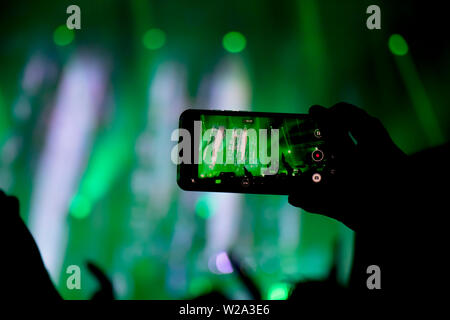 La collecte de mémoire numérique perd de capacité d'être présent, silhouette d'un homme tournage la scène de concert avec son smart phone Banque D'Images