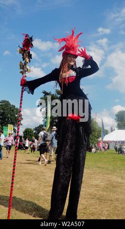 Grand parc Tew, Chadlington, Oxfordshire, UK. 7 juillet 2019. Femme sur pilotis divertit la foule à Cornbury Festival de musique. Crédit : Laura Downs/Alamy Live News Banque D'Images