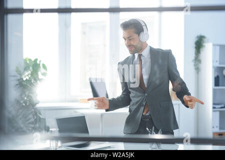 Homme d'affaires dynamique dans les écouteurs et soirée danse à la rupture Banque D'Images