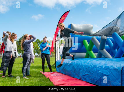 Défi du labyrinthe, Dalkeith Country Park, Midlothian, Ecosse, Royaume-Uni. Femme de sauter plus longue course d'obstacles gonflable Banque D'Images
