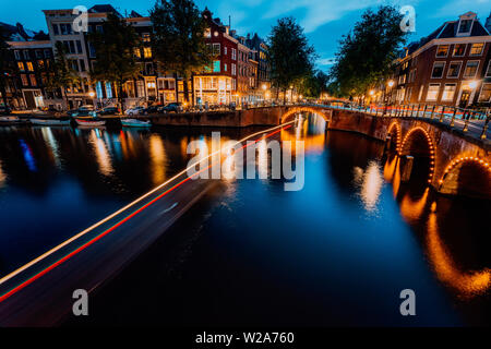 Amsterdam city centre-ville illuminée le soir. Bateau touristique tout en légèreté et pont réflexions à la Leidsegracht et Keizersgracht. Long Banque D'Images