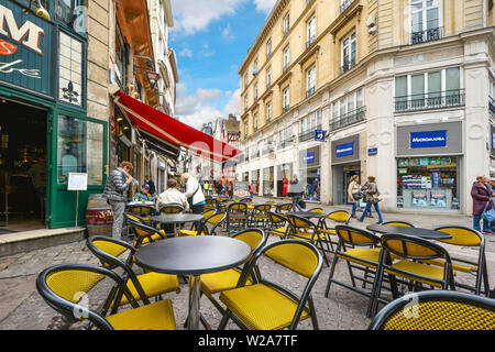 Un café-terrasse avec chaises jaune sur la rue touristique principale Gros Horloge dans la ville de Rouen en Normandie France Banque D'Images