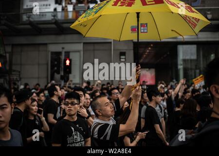 Un homme tient un parapluie jaune comme un symbole de la démocratie de Hong Kong au cours de la protestation contre la loi sur l'extradition vers la Chine. Banque D'Images