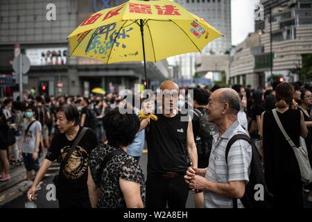 Un homme tient un parapluie jaune comme un symbole de la démocratie de Hong Kong au cours de la protestation contre la loi sur l'extradition vers la Chine. Banque D'Images