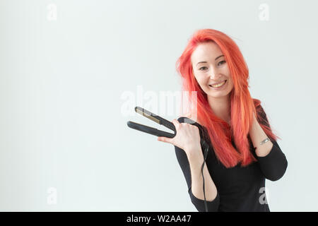 Salon de beauté, coiffure et personnes concept - jeune femme avec des cheveux colorés holding fer à friser sur fond blanc Banque D'Images