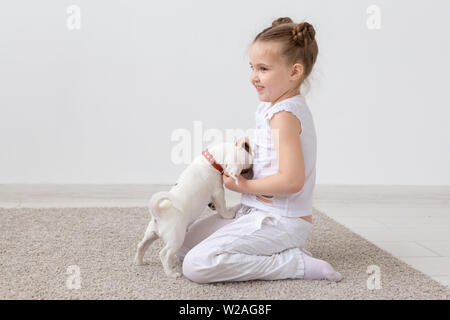 Animal de compagnie, les enfants et animaux - concept enfant fille assise sur le sol et l'alimentation chiot Banque D'Images